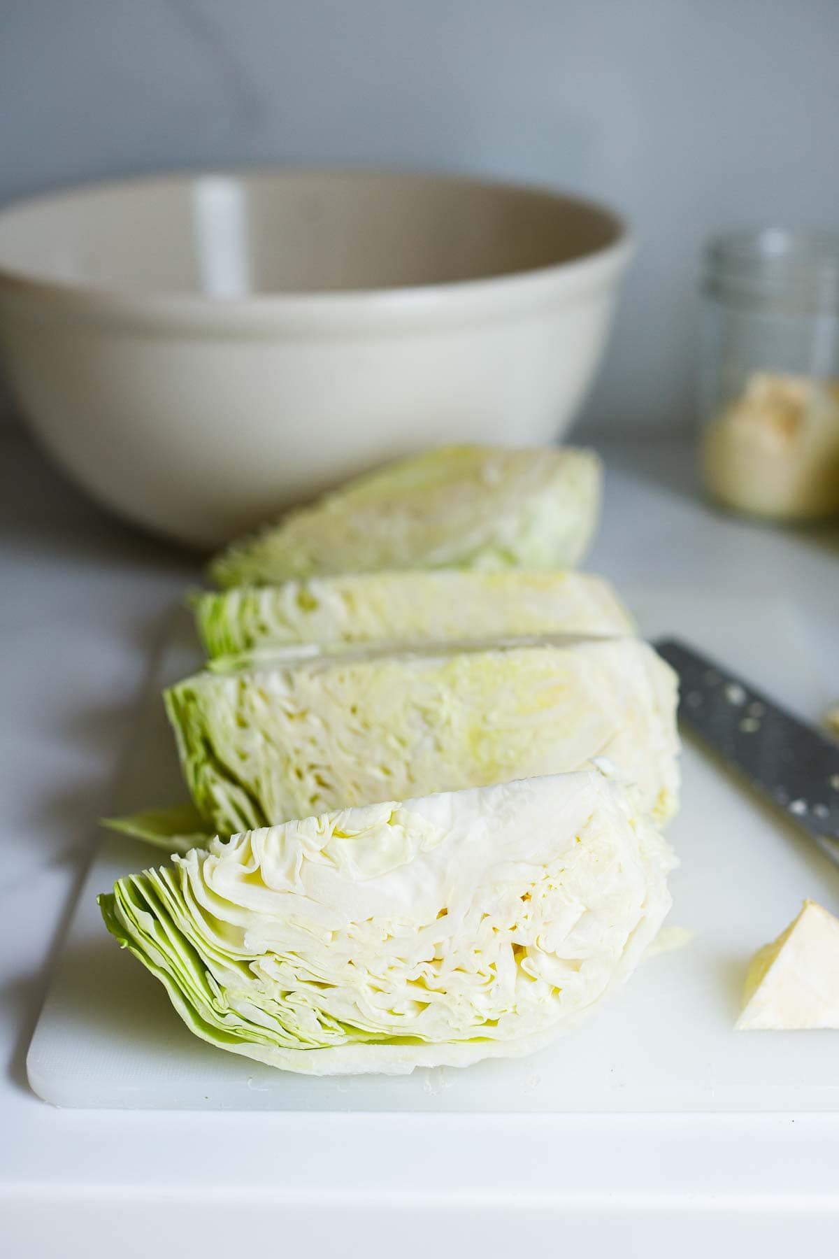 green cabbage cut into quarters on cutting board. 