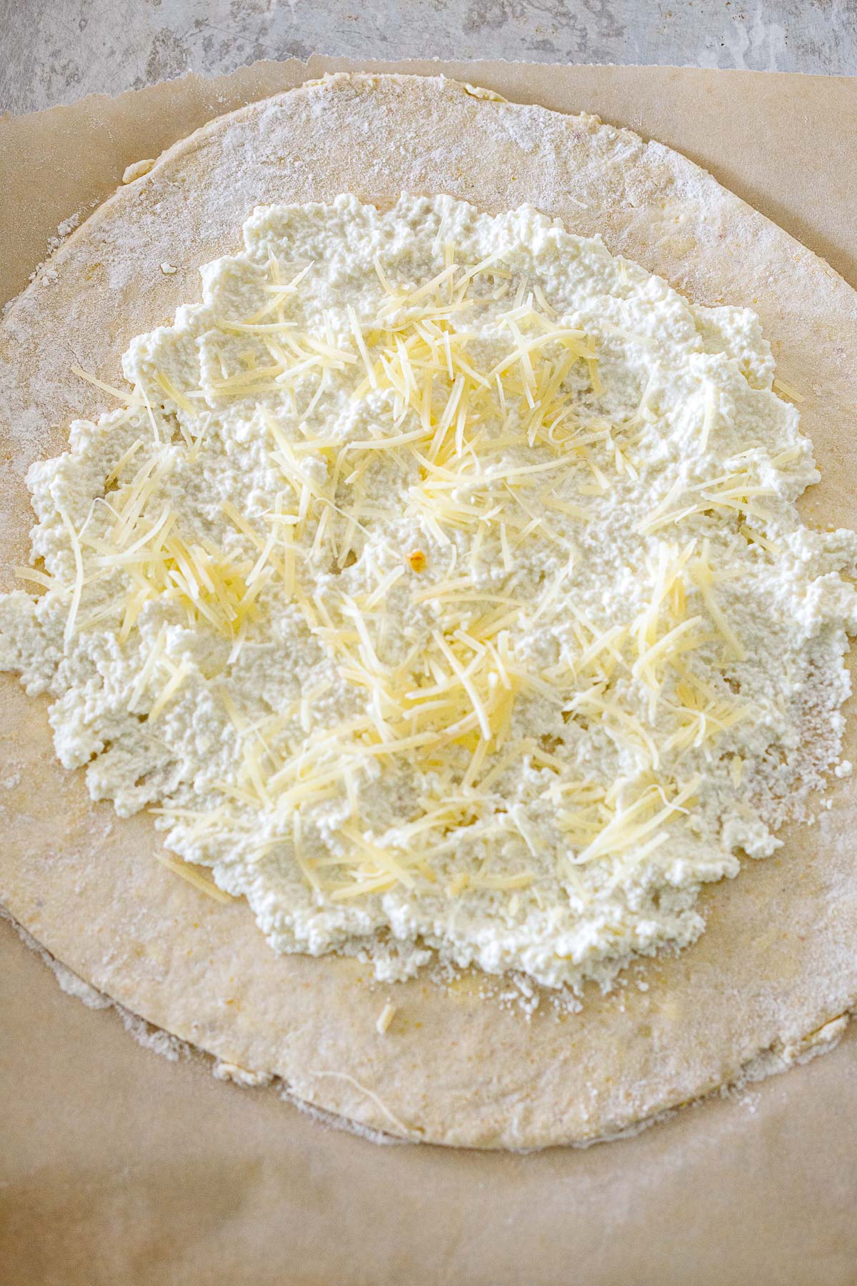 galette dough with ricotta spread evenly leaving 2 inch border with parmesan sprinkled on top. 