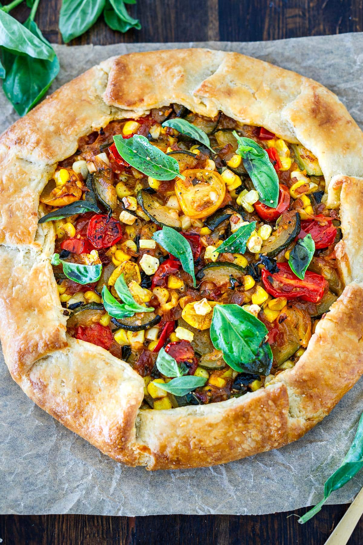 savory summer galette on parchment garnished with fresh basil. 