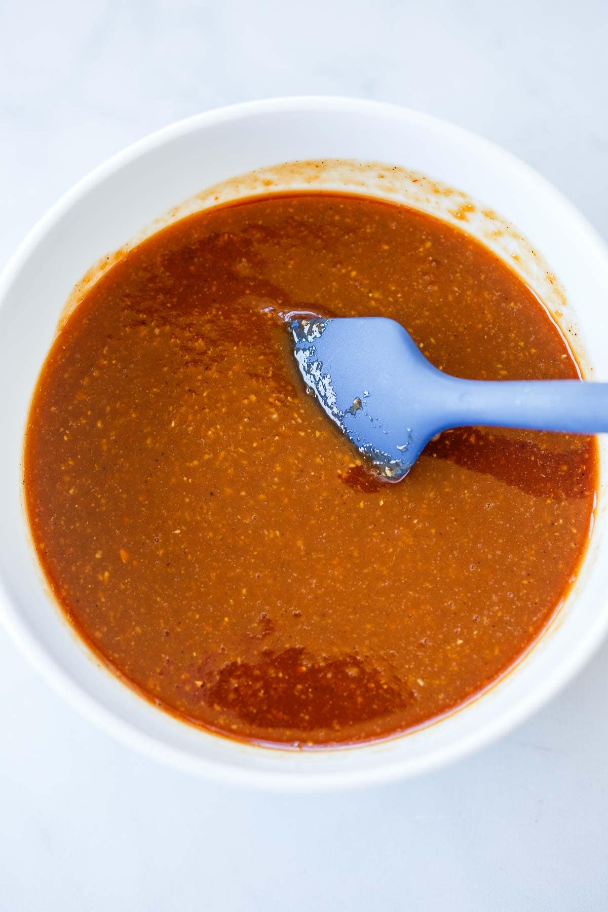 bowl of huli huli marinade with blue spatula.