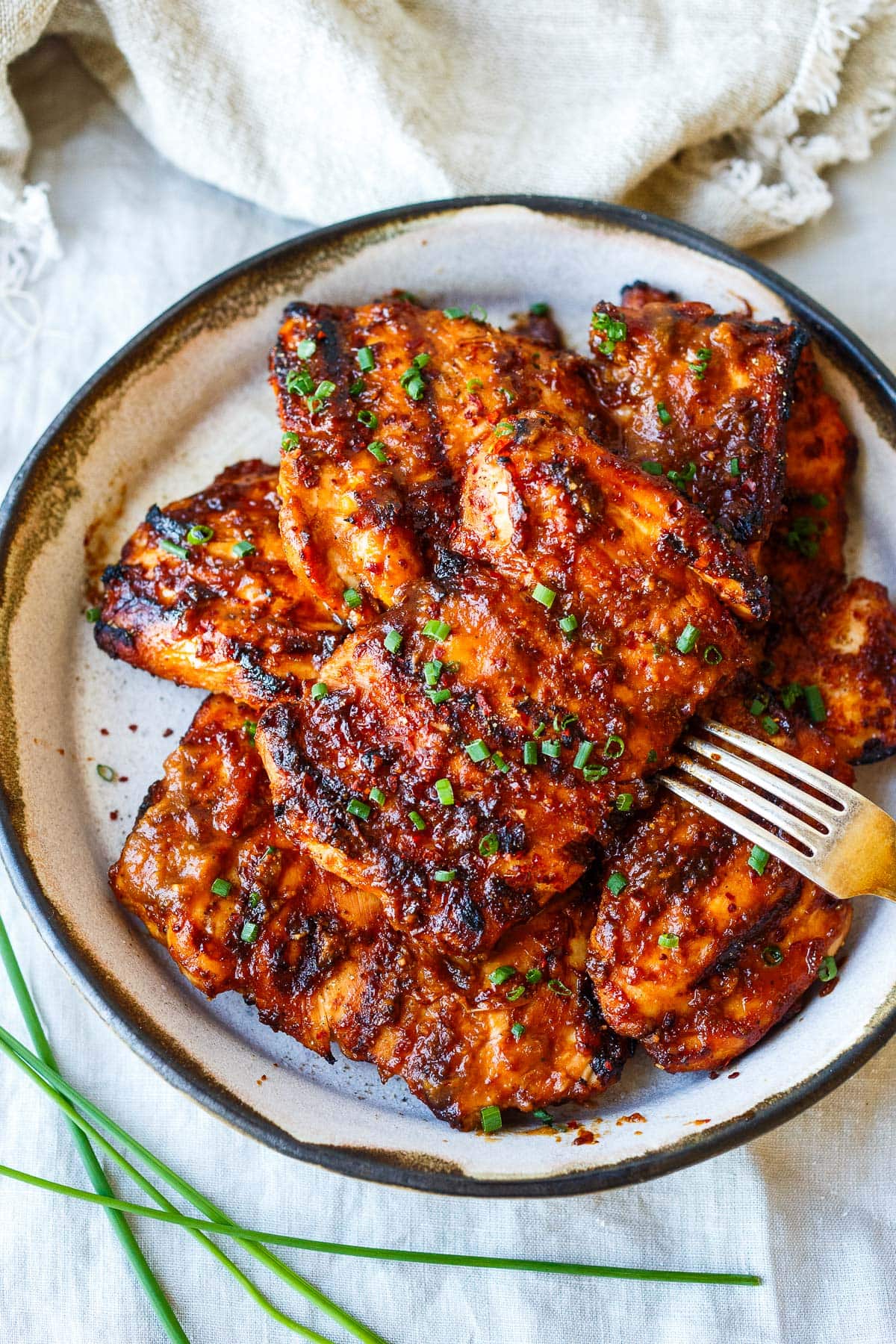 plate of grilled huli huli chicken garnished with chives.