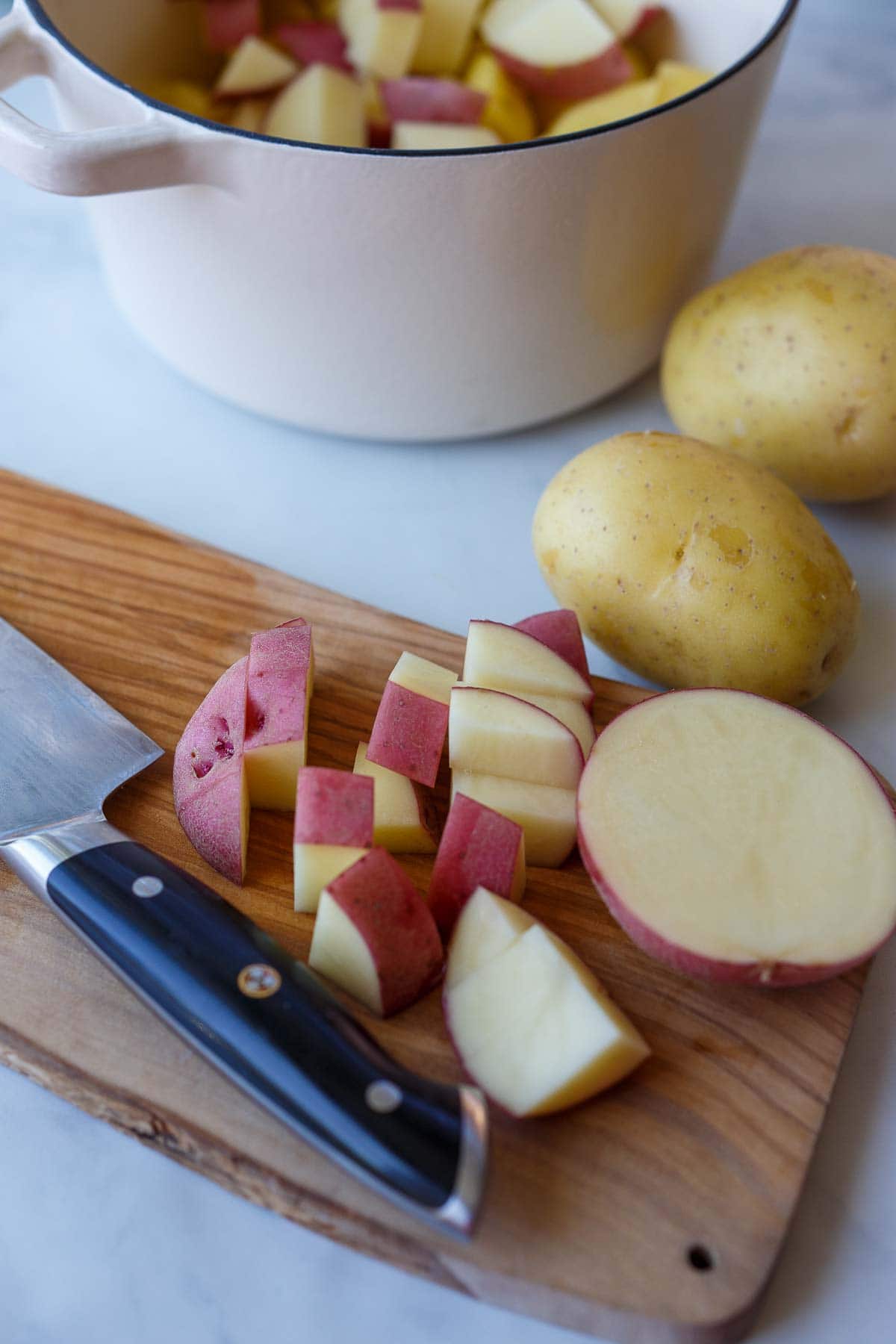 wood cutting board and knife chopping potatoes.