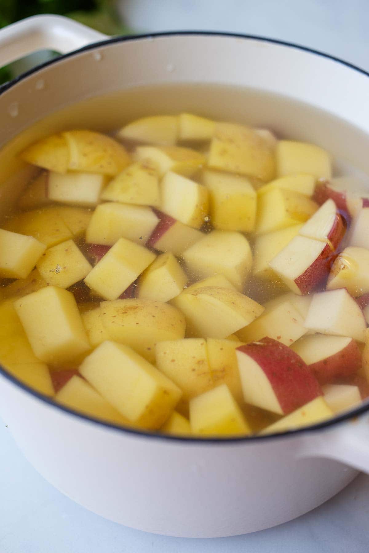 large pot with chopped potatoes and cold water.
