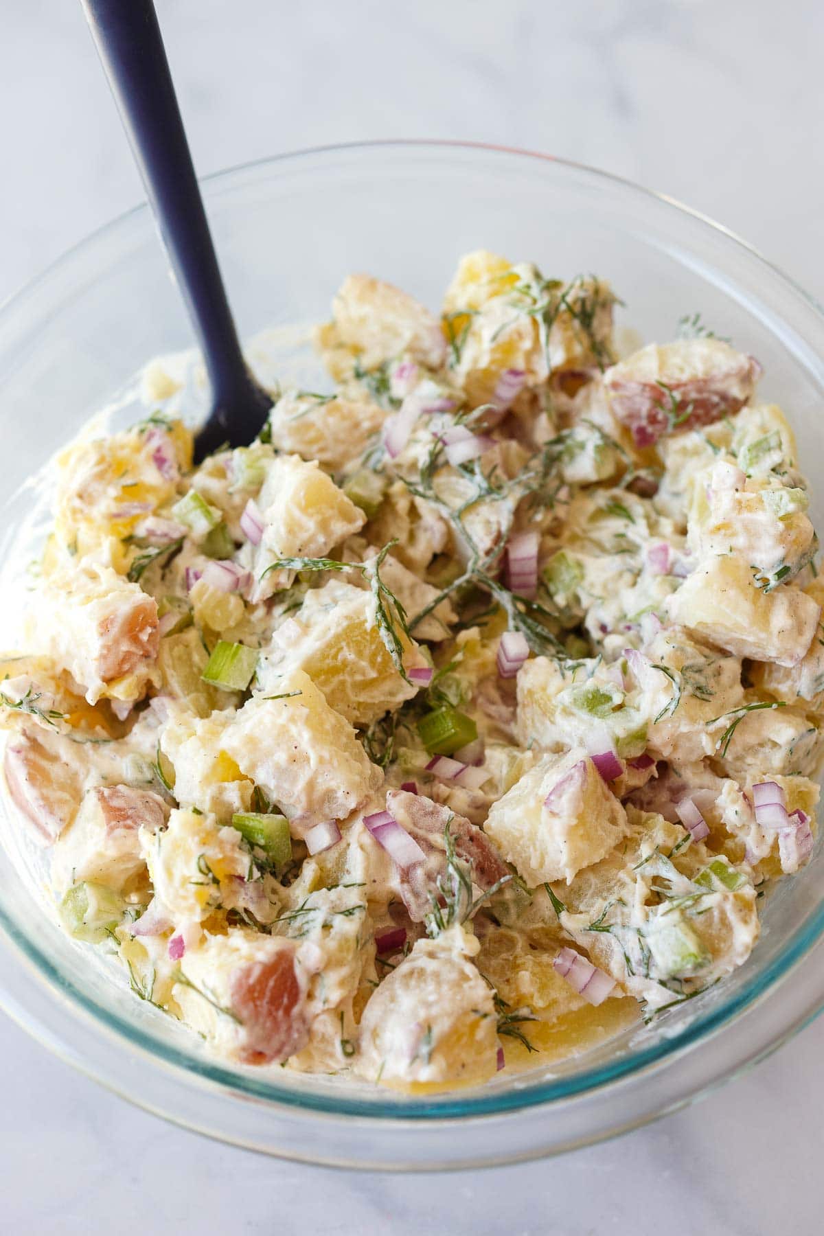 glass mixing bowl with creamy potato salad.