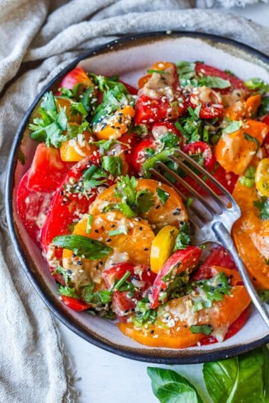 This Sesame Tomato Salad is an easy, delicious way to savor ripe, juicy heirloom tomatoes! It's drizzled with a flavorful sesame ginger dressing, fresh basil, and toasted sesame seeds. Vegan and gluten-free.