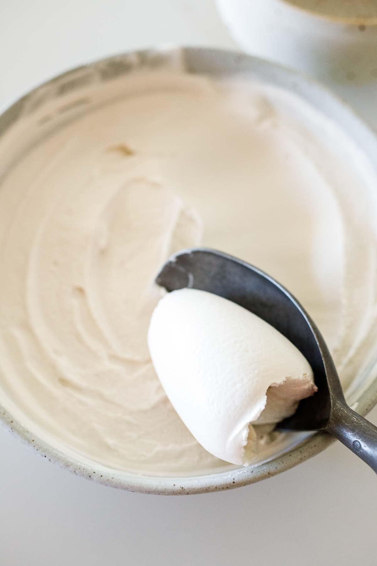 ice cream scoop lifting spoonful of dairy-free ice cream from bowl. 