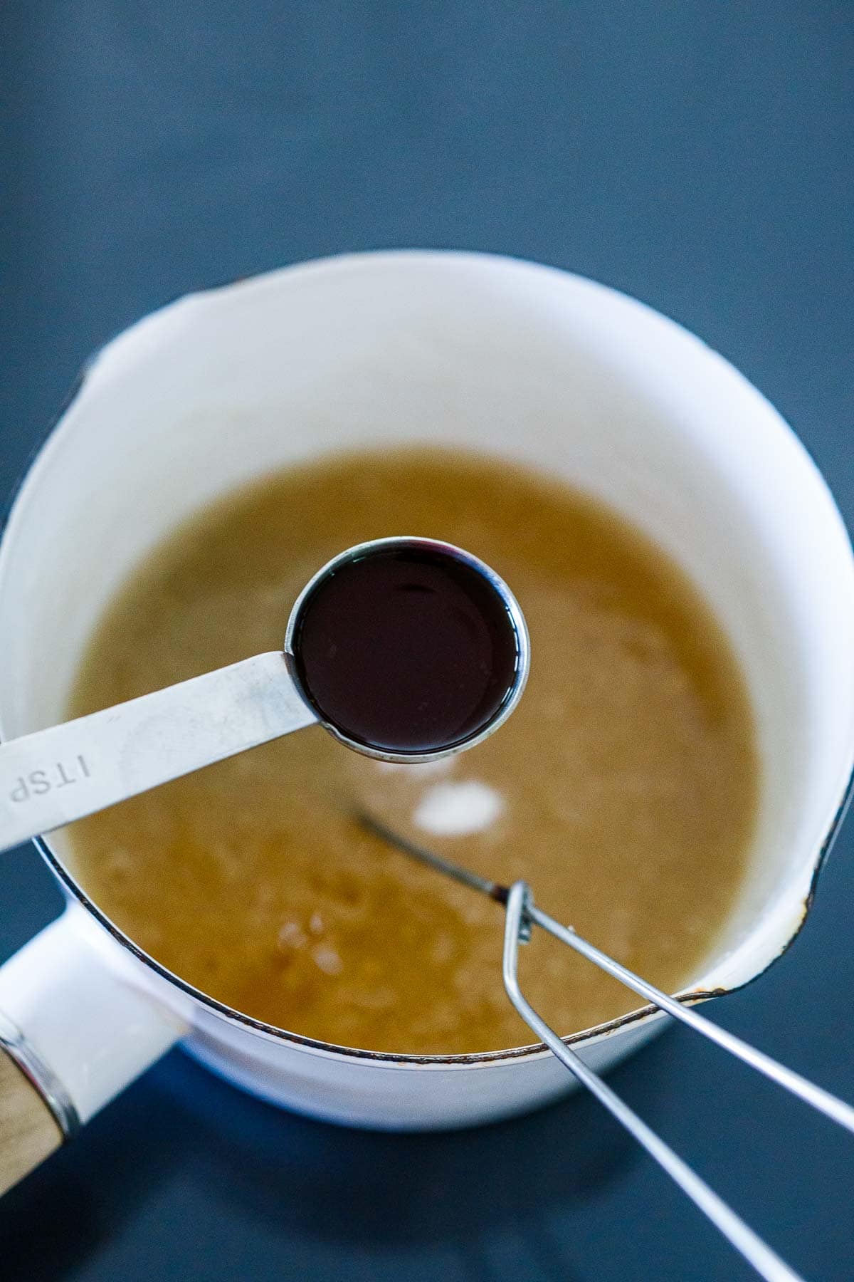 holding teaspoon of vanilla over saucepan with sugar mixture.