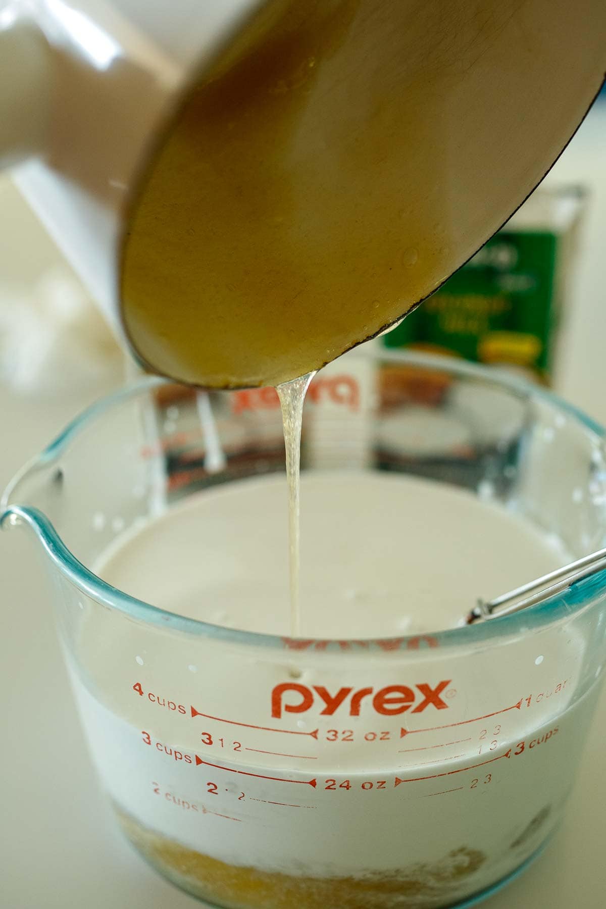 pouring sugar mixture into measuring cup with coconut milk.