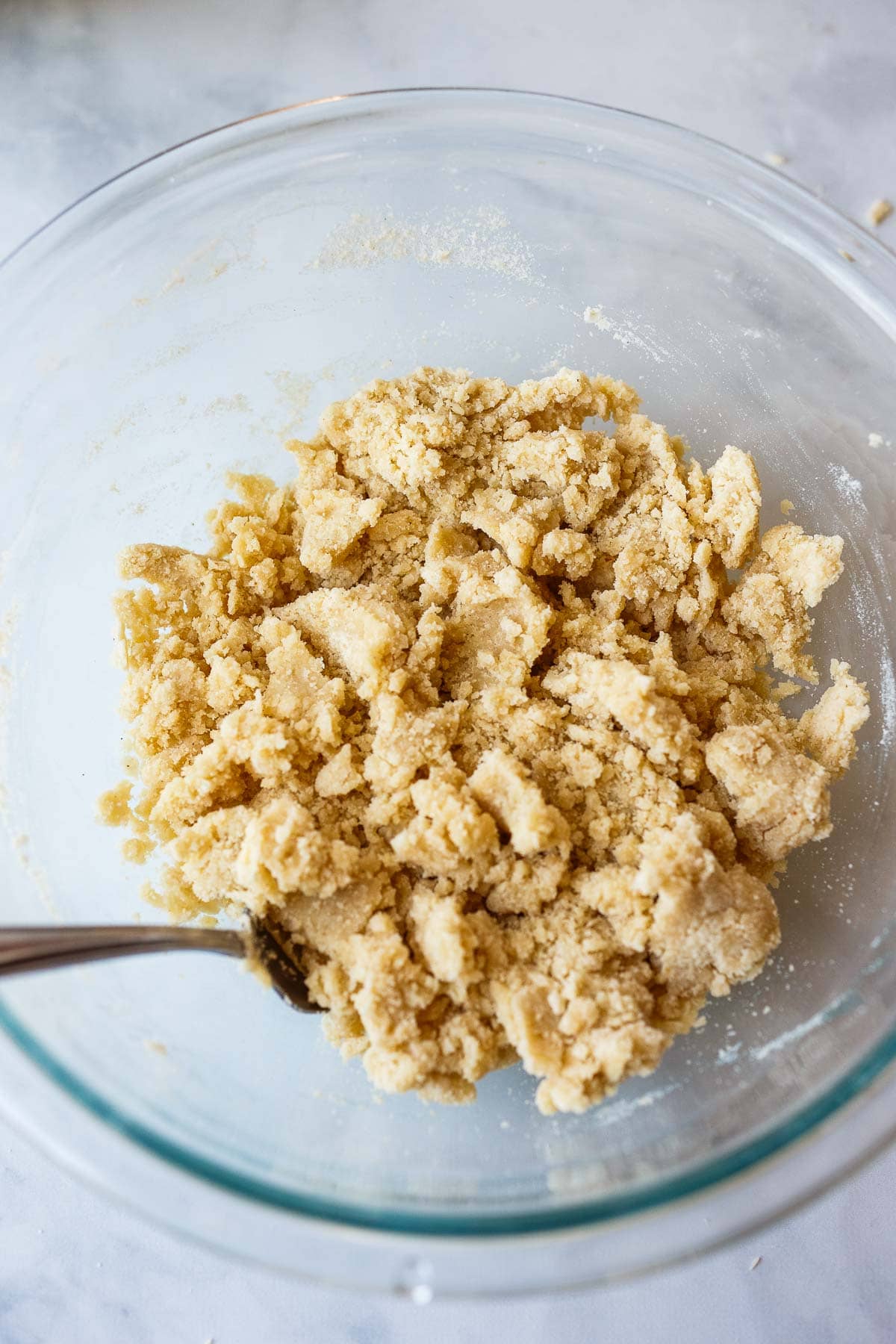 glass mixing bowl with fork mixing together vegan tart dough.
