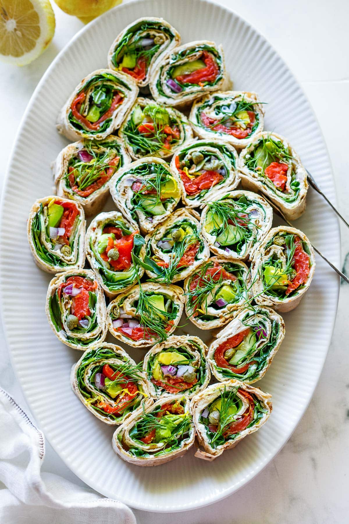 serving platter with lavash wraps and tongs, garnished with fresh dill. 