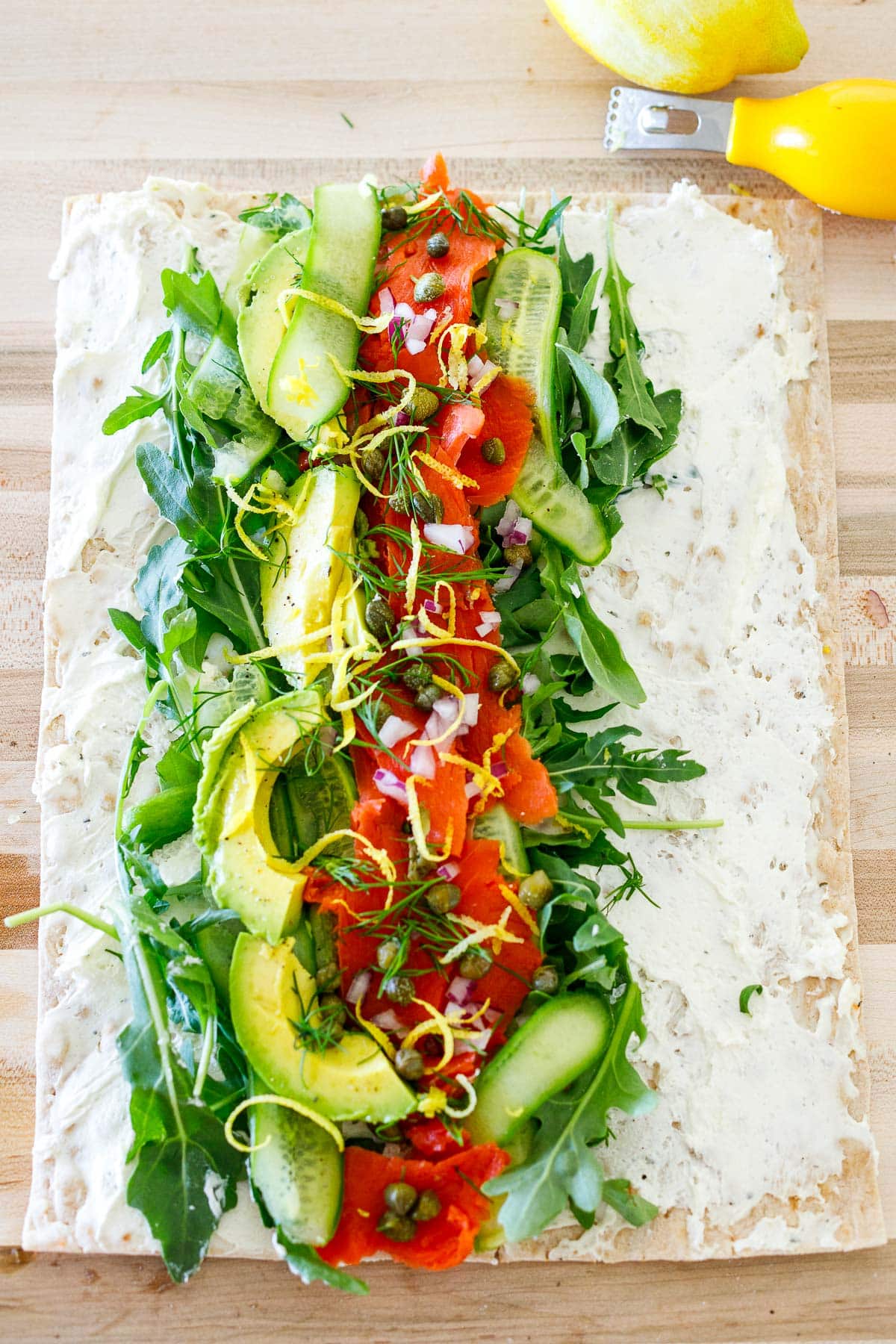 lavash bread with cream cheese topped with greens, cucumbers, smoked salmon, avocado, red onion, capers, lemon zest. 