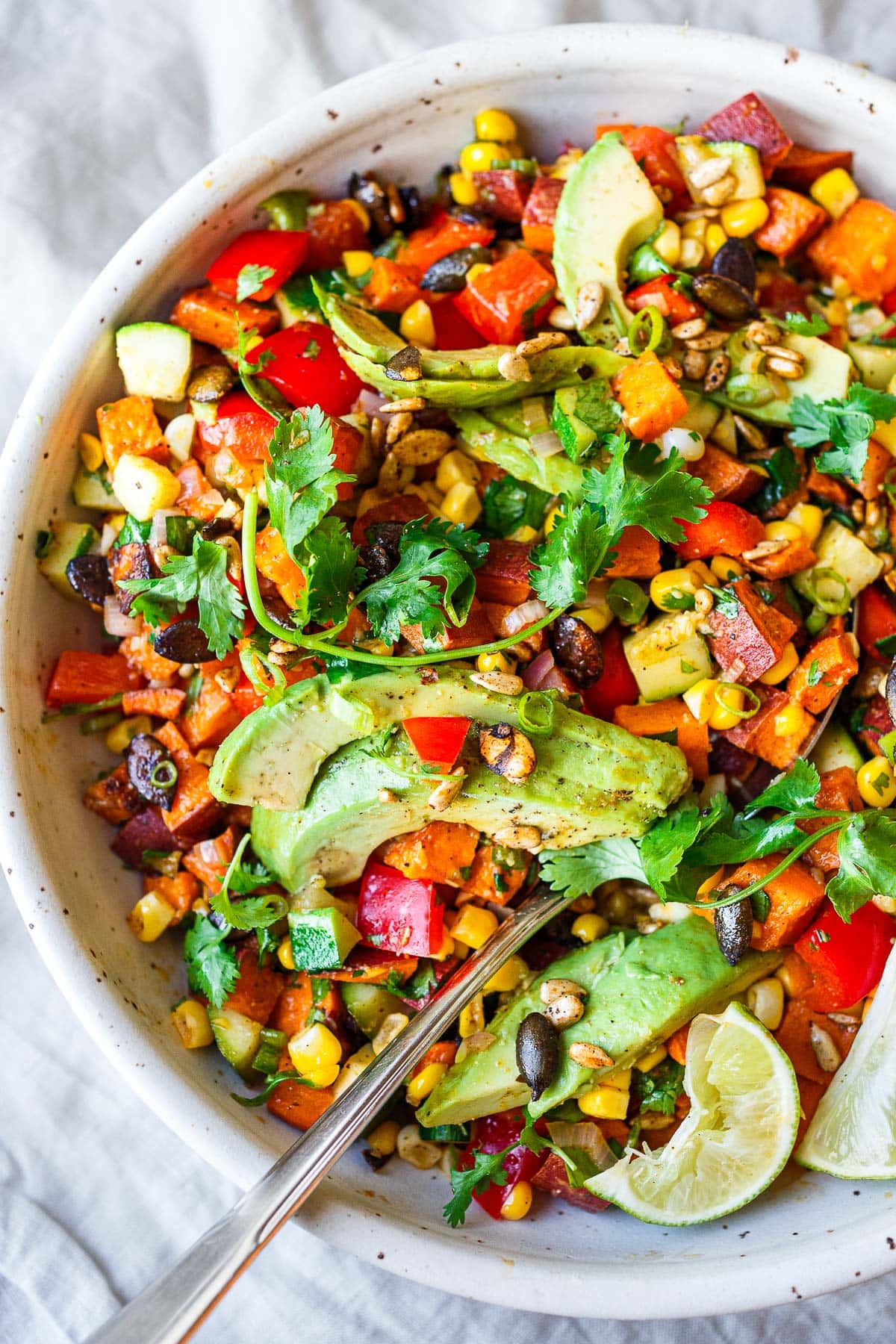 sweet potato salad topped with toasted pepitas, fresh cilantro, sliced avocado, and lime wedges. 