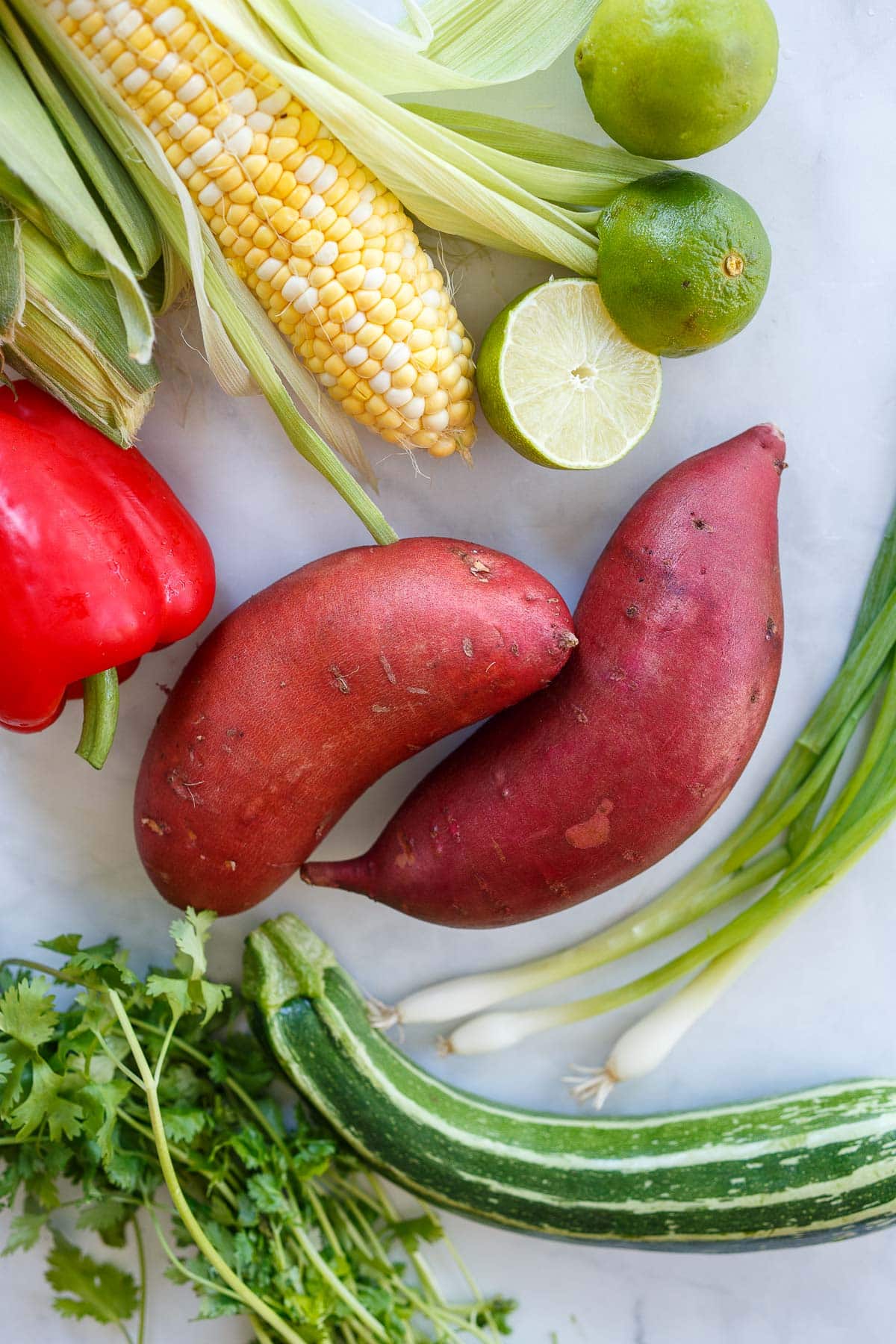 ingredients for sweet potato salad - sweet potatoes, green onions, limes, corn, bell pepper, zucchini, cilantro. 