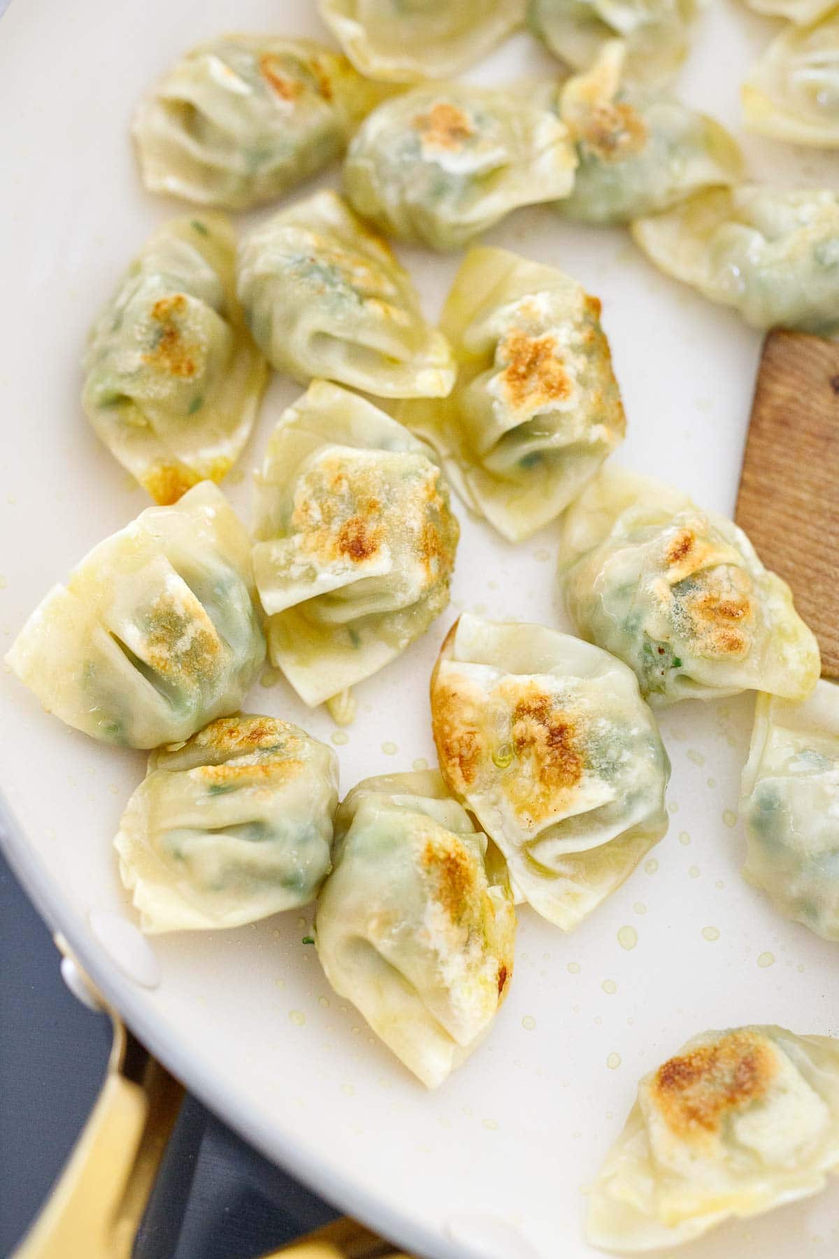 frozen mini wontons searing in skillet. 