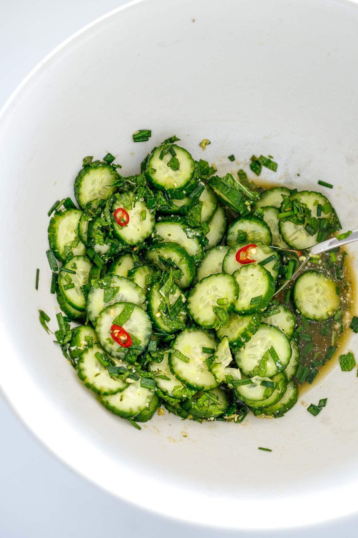 cucumber, herb, and chili salad in bowl in Asian dressing.