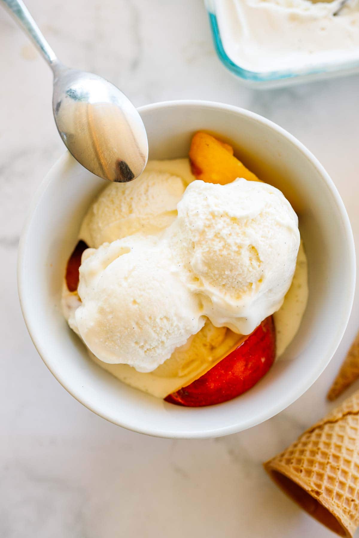 bowl of homemade ice cream with peaches and spoon.