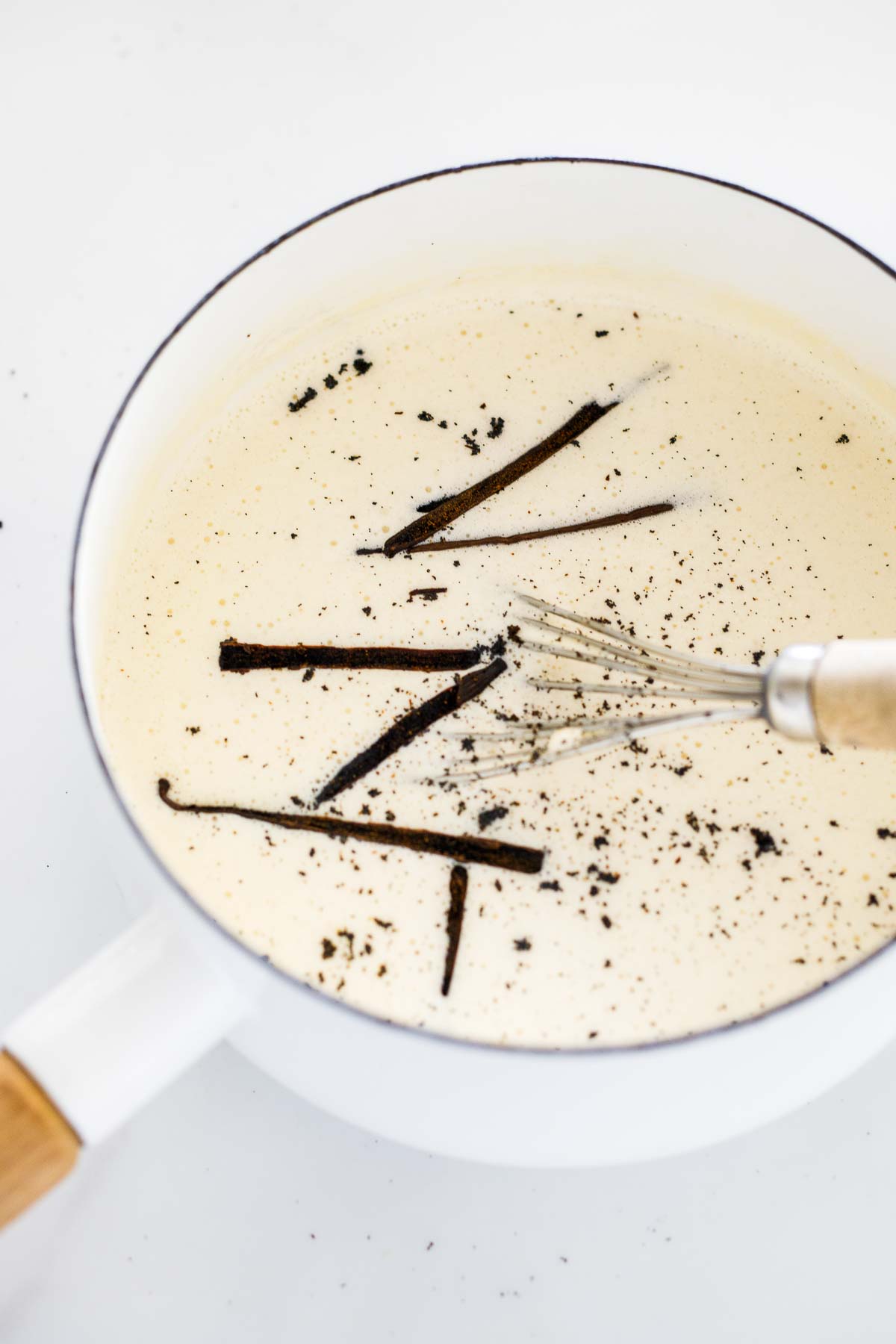 whisking vanilla bean base for ice cream in pot.