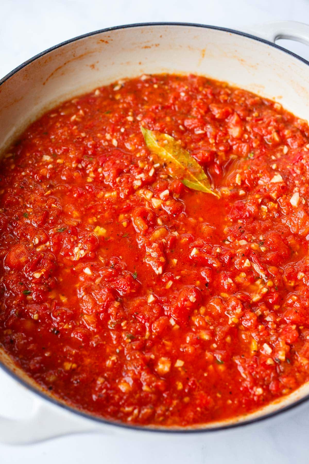 tomato sauce simmering in pan with bay leaf. 