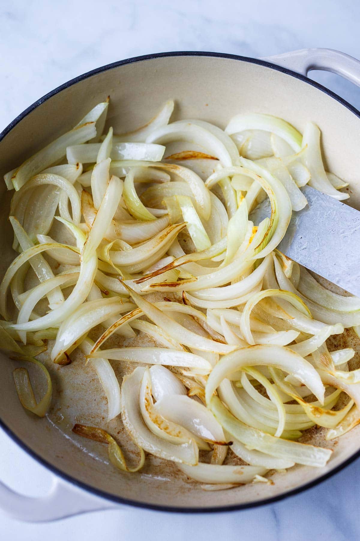 sliced onions sautéing in pan.
