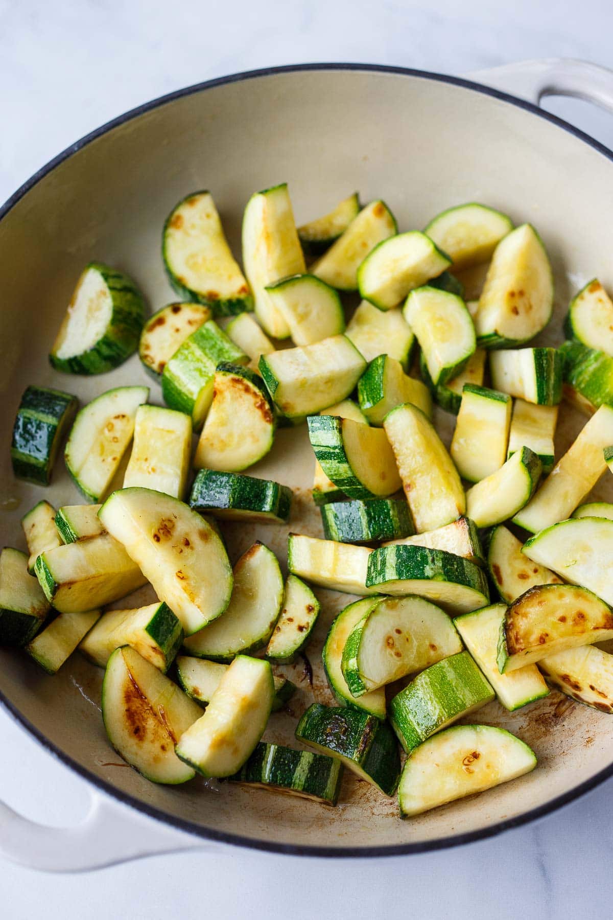 chopped zucchini sautéing in pan.