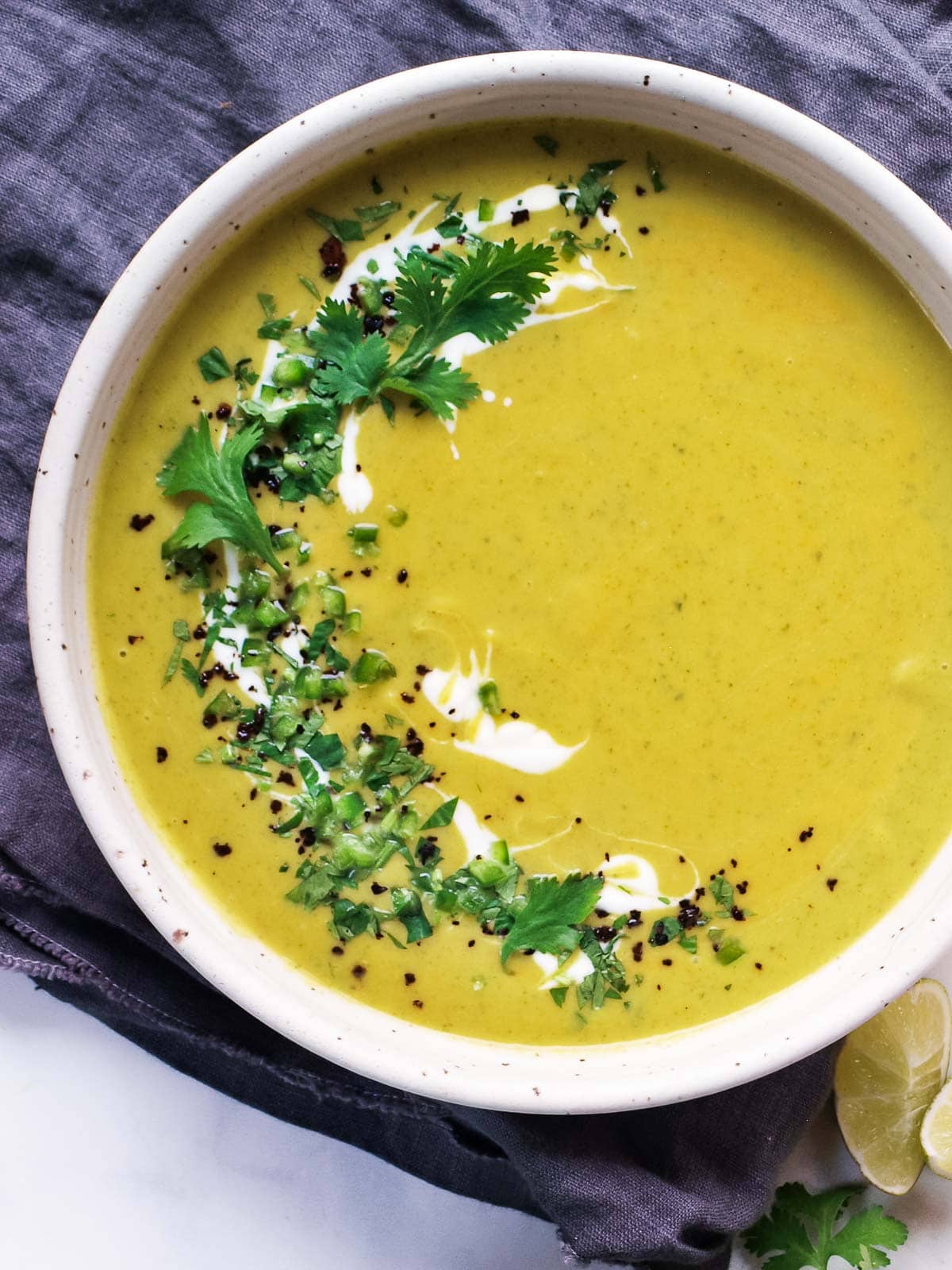 Curried Zucchini Soup in a bowl with herbs and yogurt. 