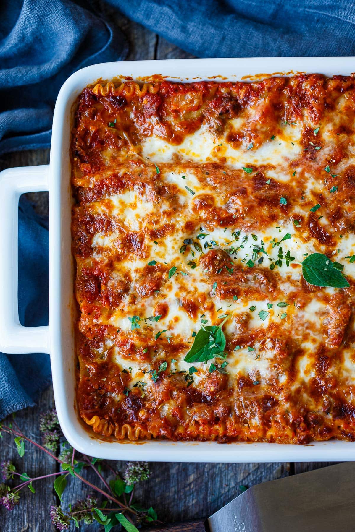 baked lasagna in baking dish, browned on top and garnished with fresh herbs.