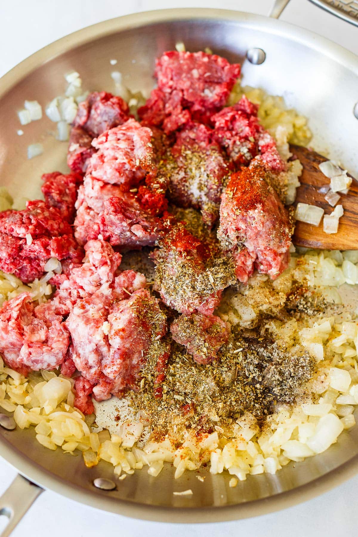 skillet with sautéed onions, ground pork, ground beef, and spices.