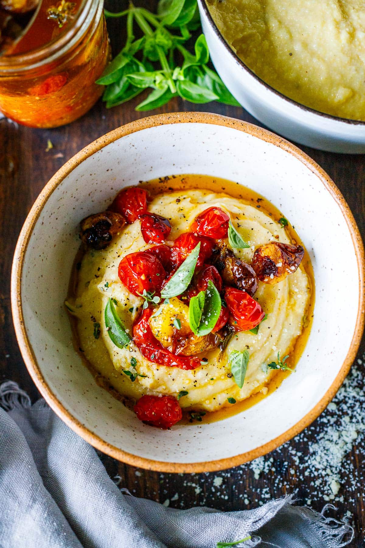 bowl of creamy polenta topped with tomato confit and fresh basil.