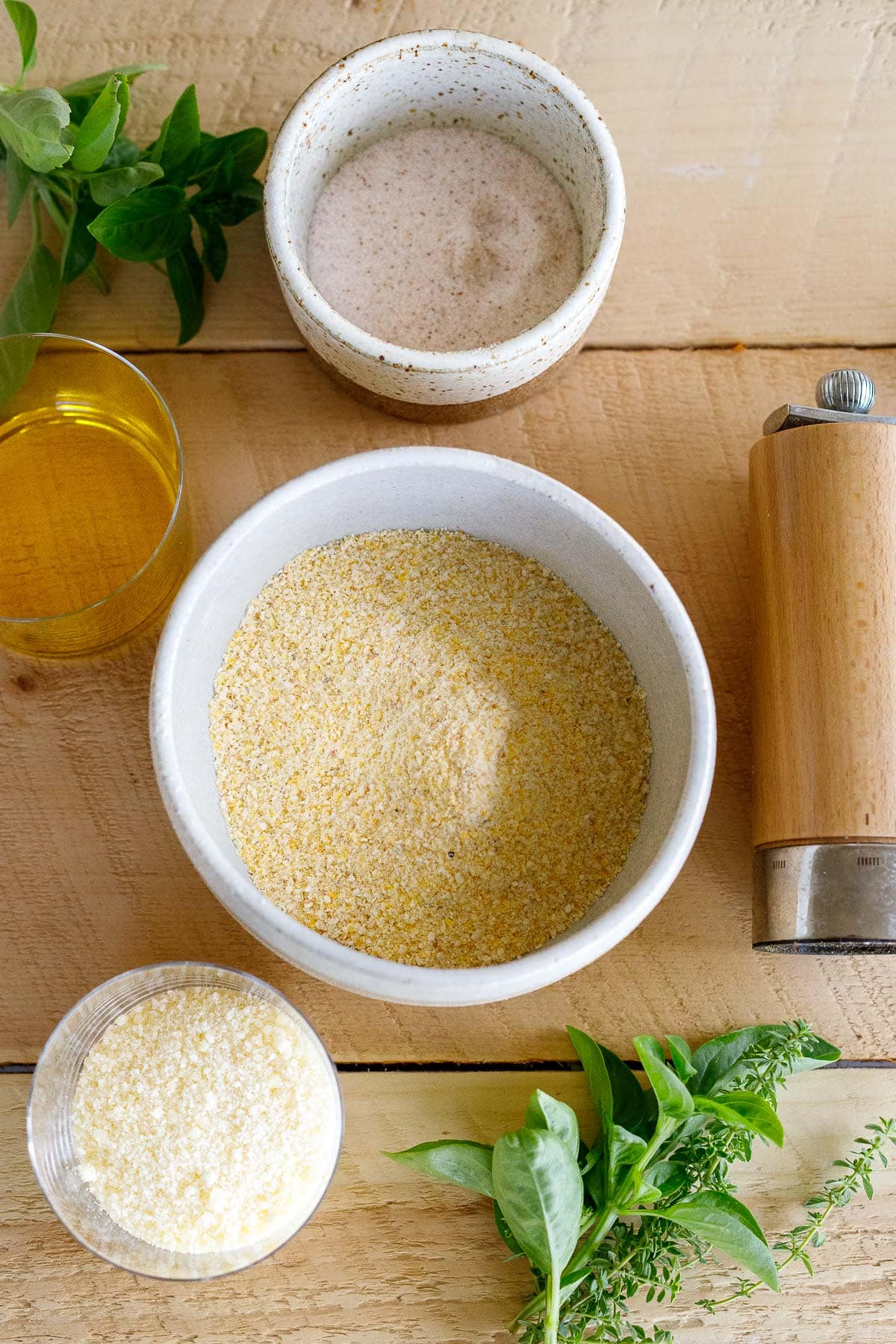 ingredients for creamy polenta - bowl of salt, fresh herbs, jar of oil, bowl of cornmeal, pepper grinder, bowl of parmesan.