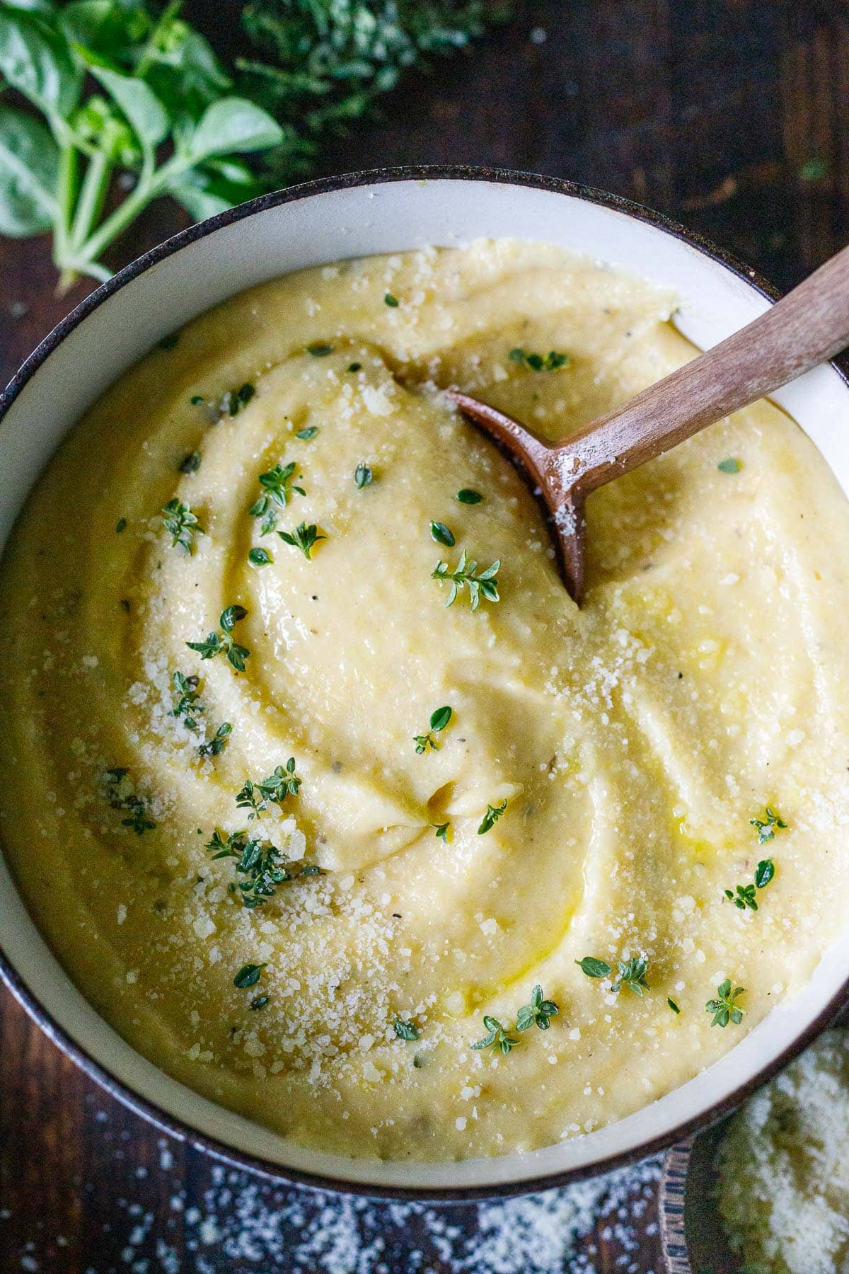 large pot with creamy polenta topped with parmesan and fresh herbs.