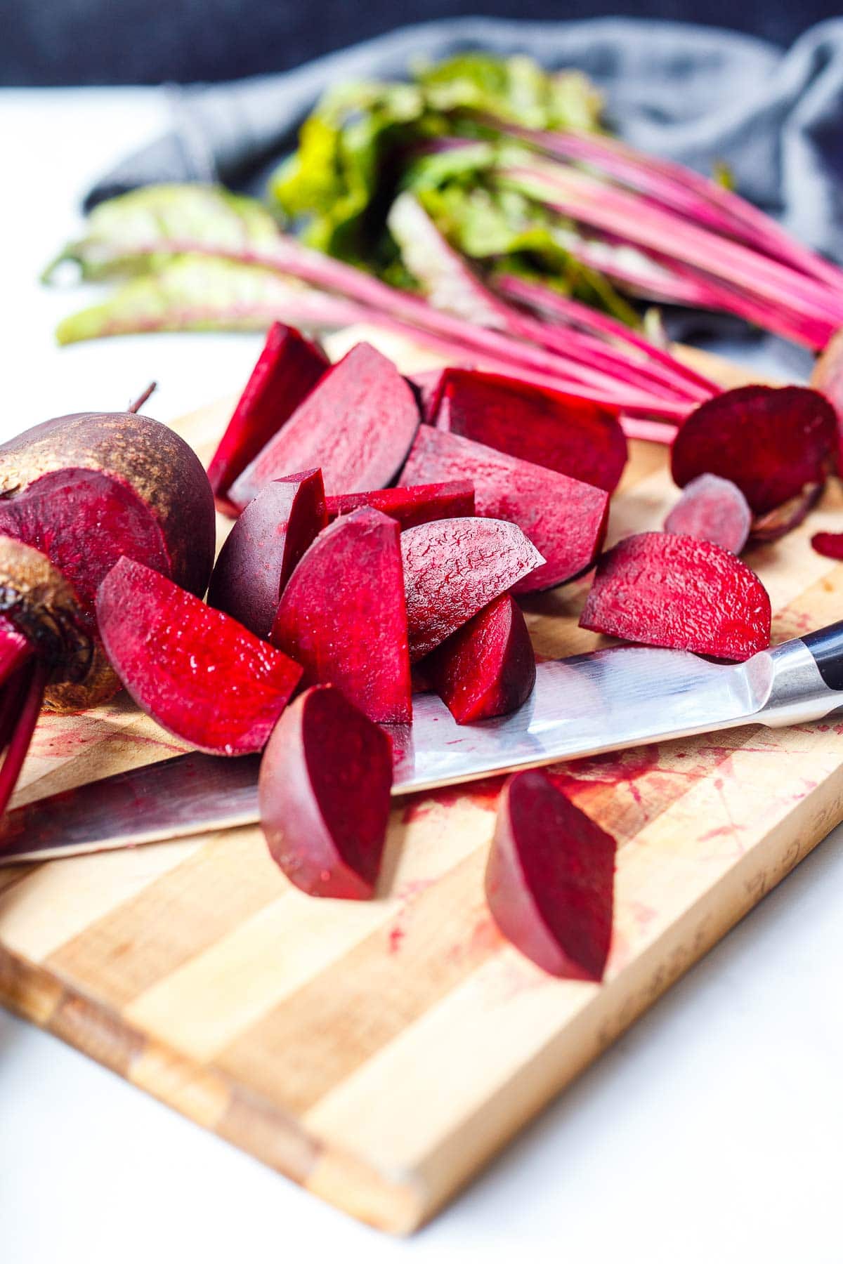 wood board with sharp knife and fresh beets cut into wedges.