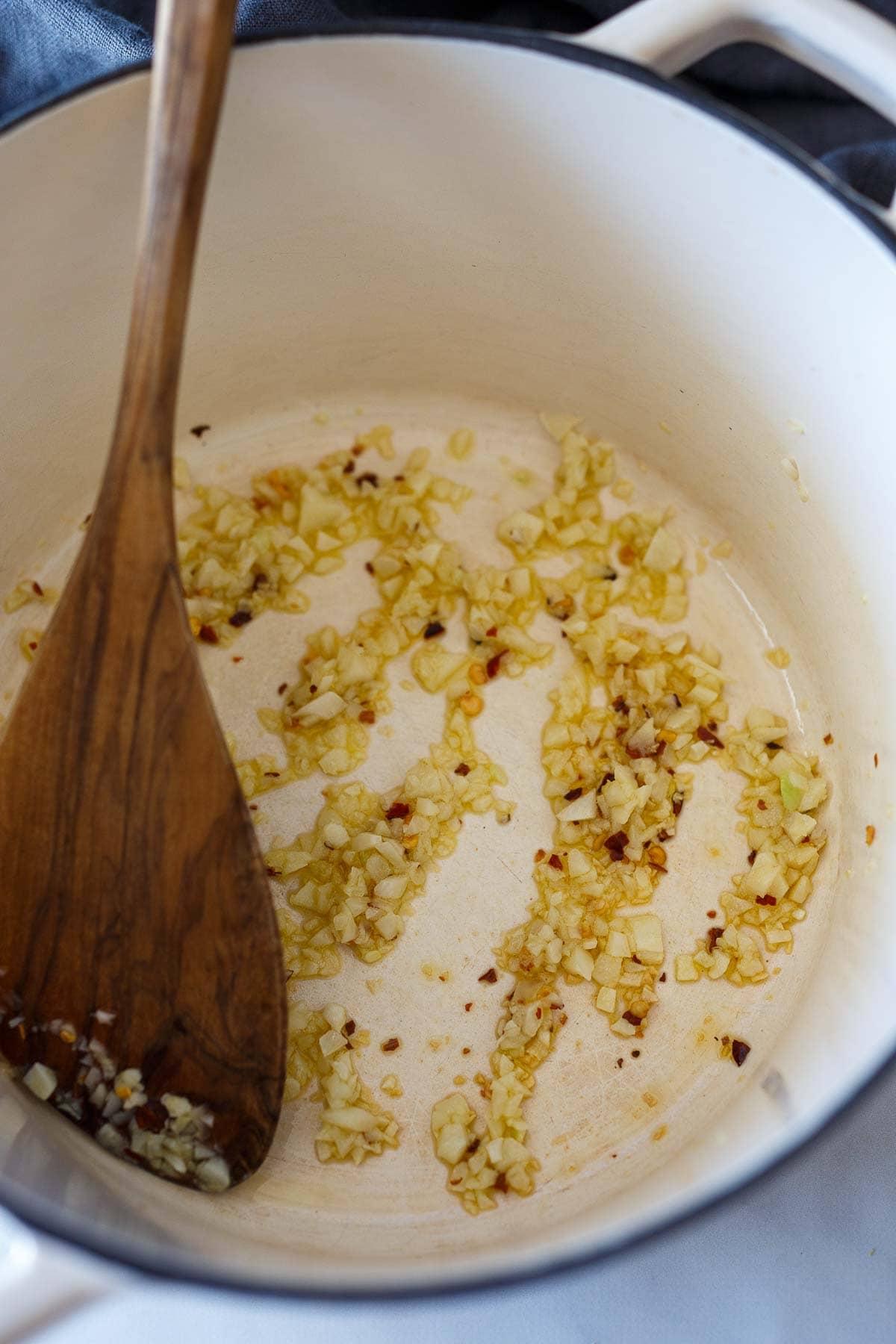 pot with sautéed garlic and red pepper flakes, stirred with wooden spatula. 