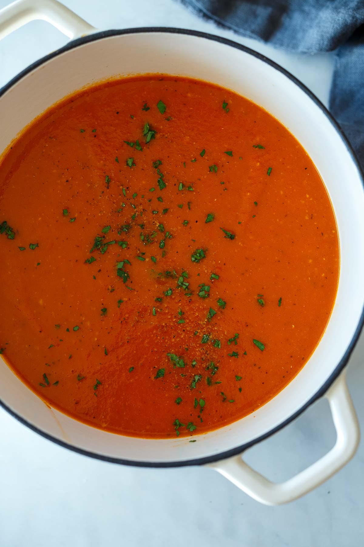 roasted red pepper tomato soup in pot with fresh herbs. 