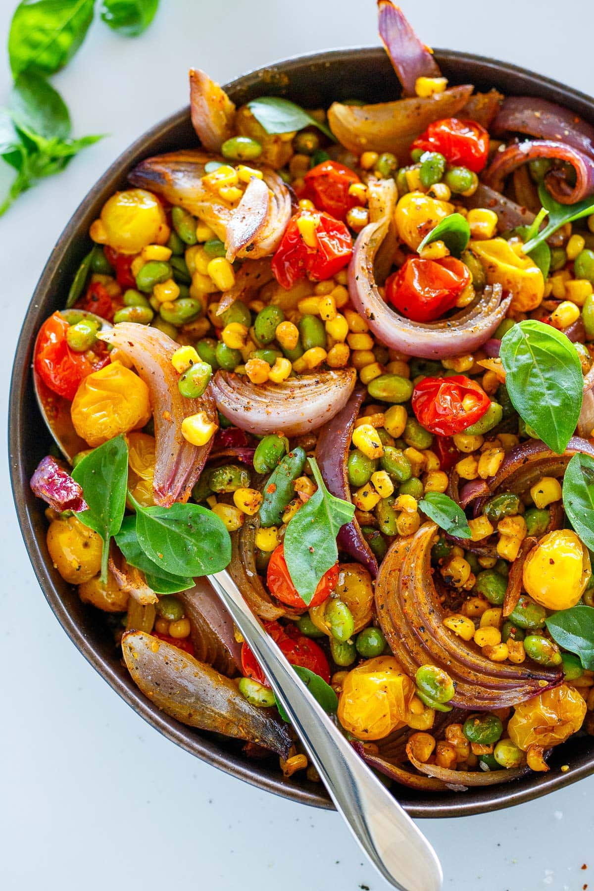 serving bowl with succotash topped with fresh basil.