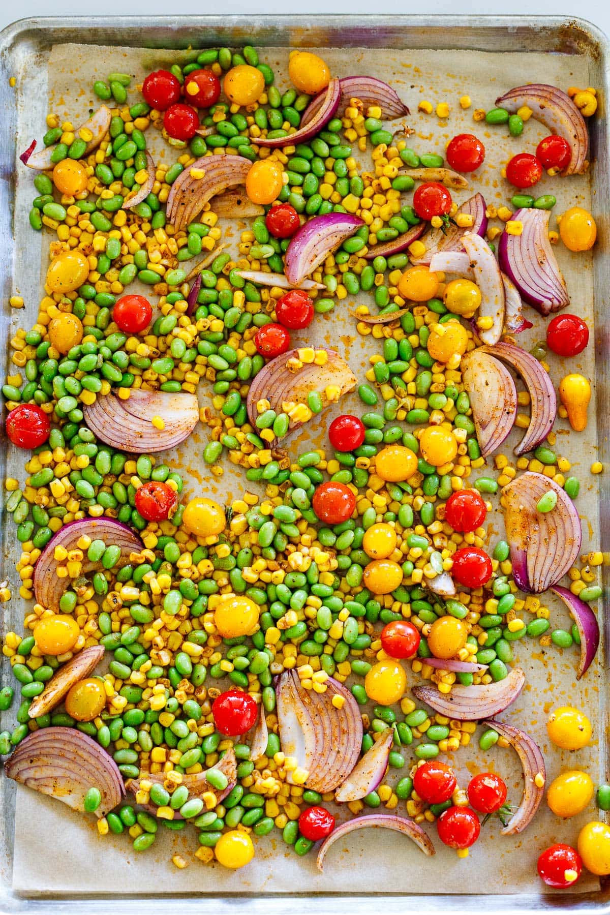 parchment lined sheet pan with succotash ingredients spread out.