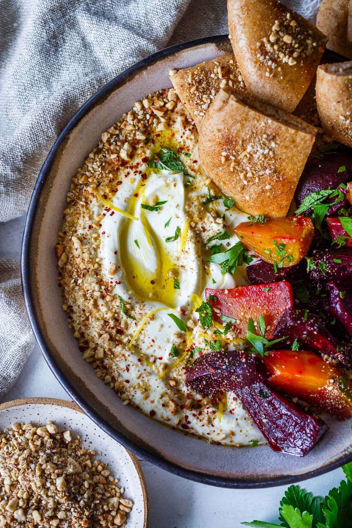 whipped feta in serving dish topped with olive oil, lemon zest, and dukkah, served with pita, and roasted beets.