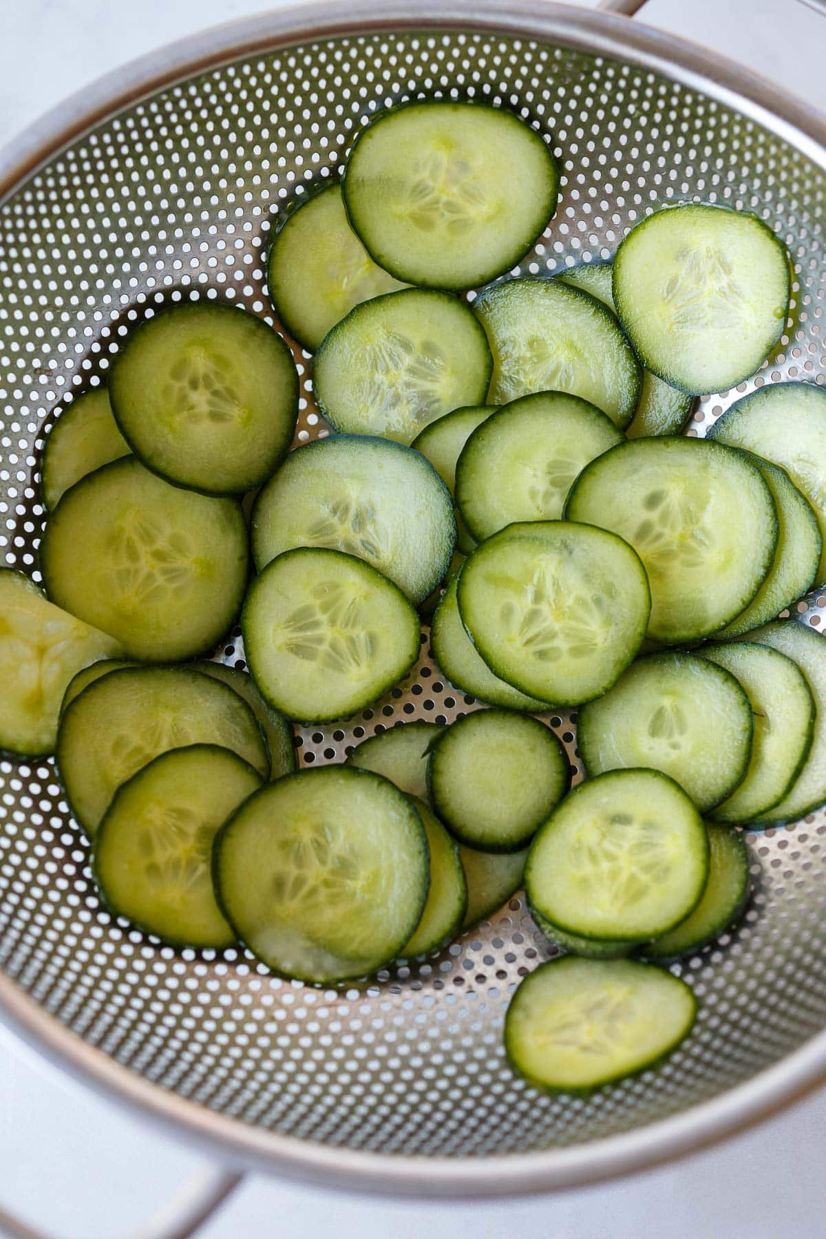 colander with salted cucumber slices.