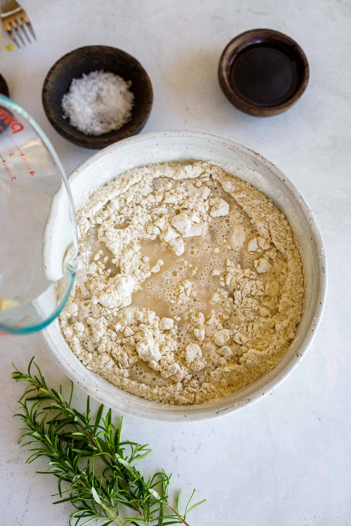 pouring water into mixing bowl with flour.