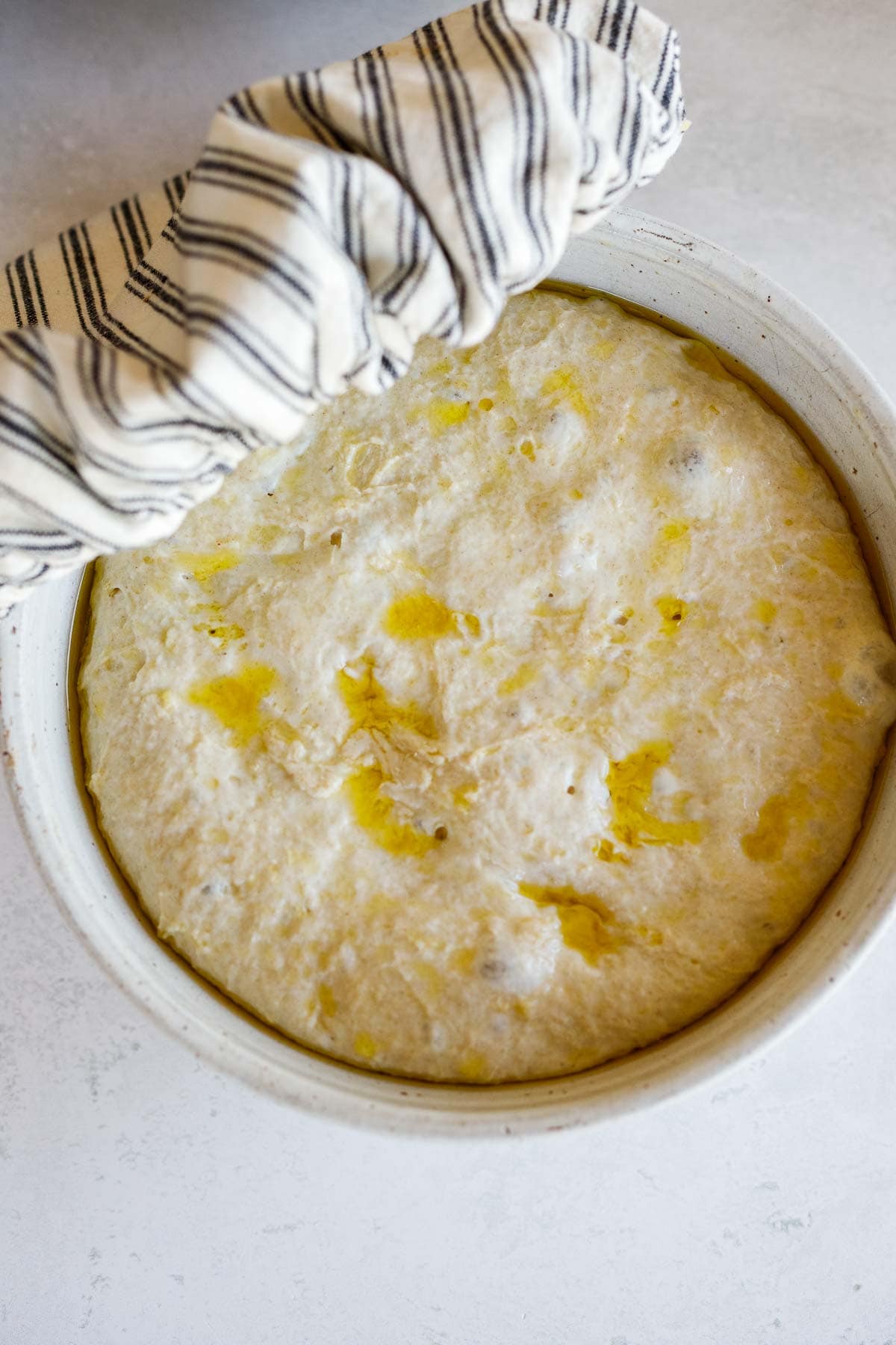 placing towel over bowl with focaccia dough.