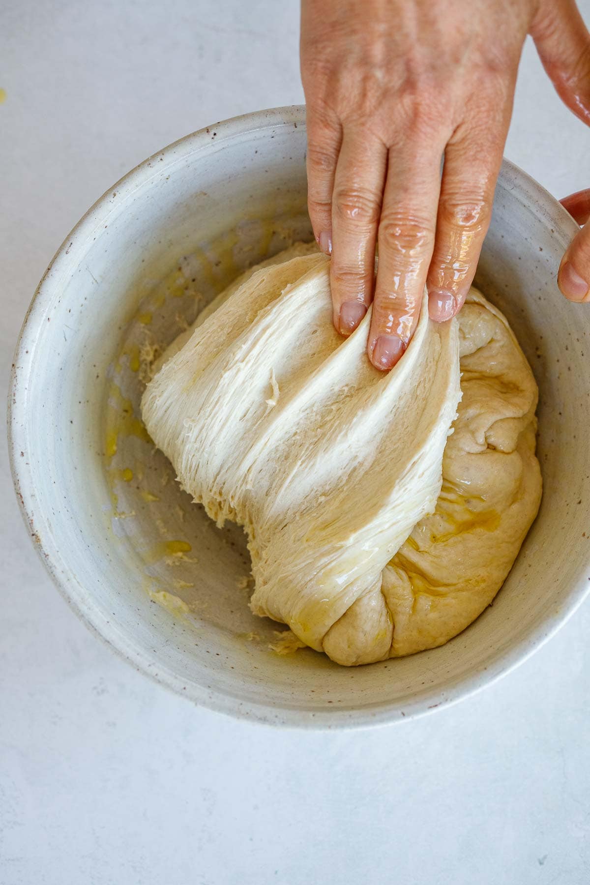 oiled hand folding dough to form a ball.