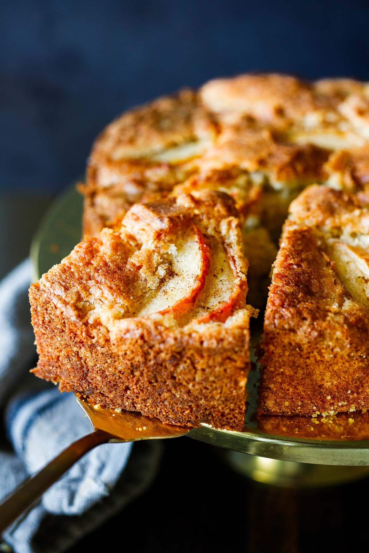 apple cake on cake stand with cake spatula pulling away a slice. 