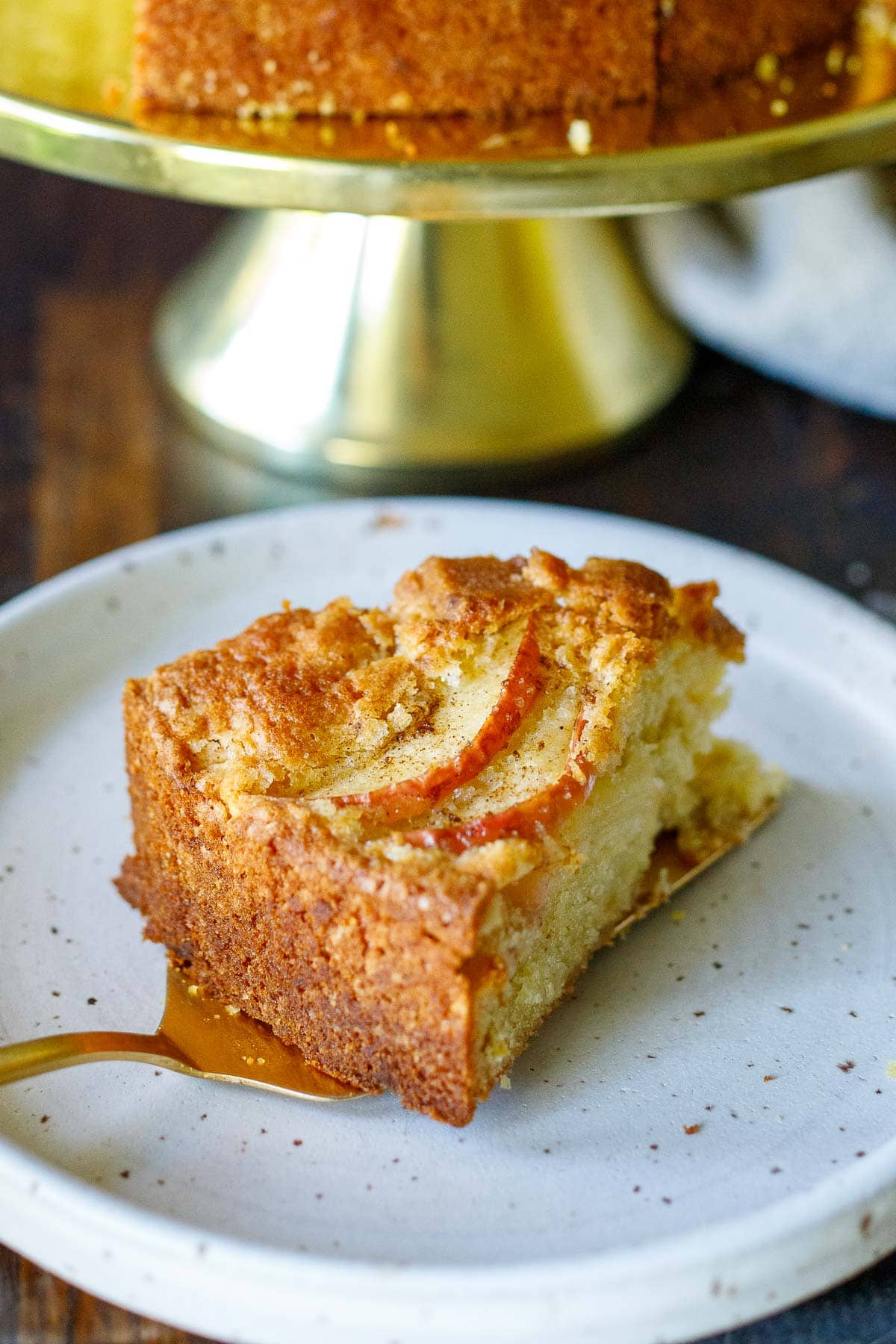 cake spatula laying apple cake slice down onto plate. 