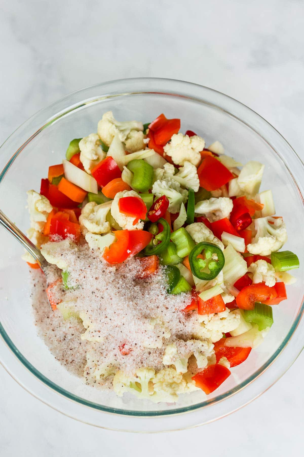 glass mixing bowl with chopped veggies and salt. 