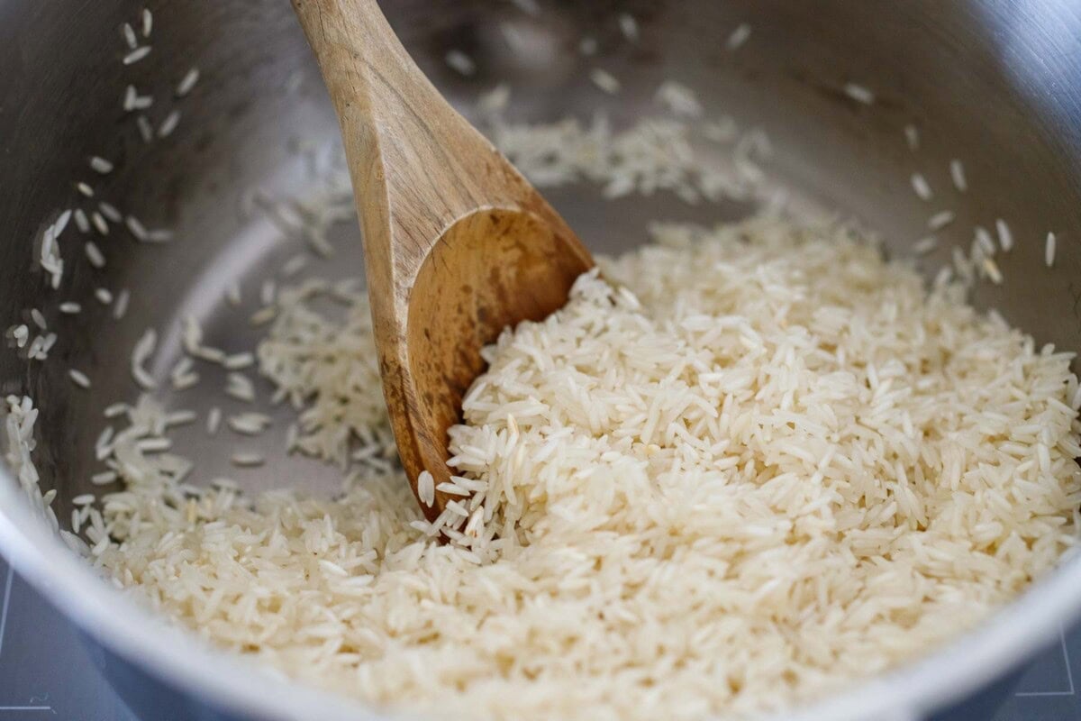 wood spoon stirring basmati rice in pot. 