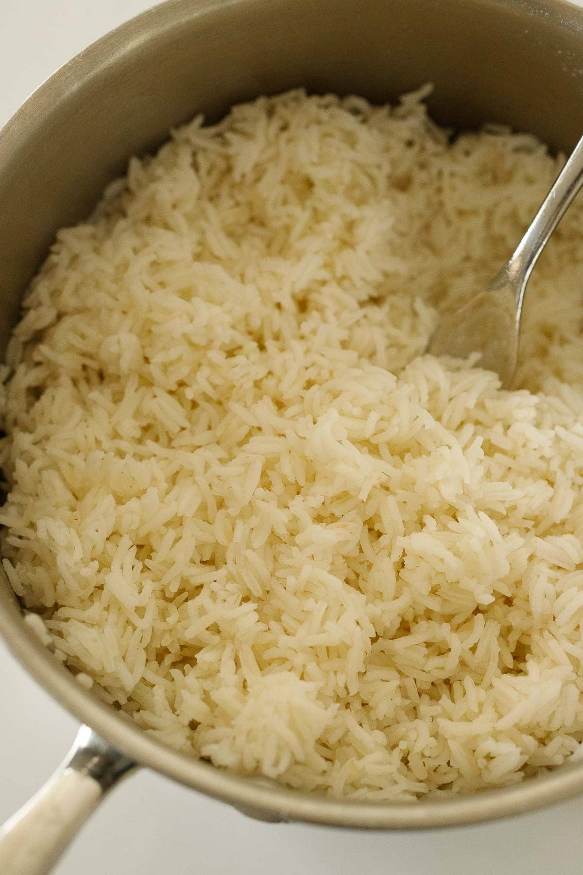 fork fluffing cooked basmati rice in pot. 