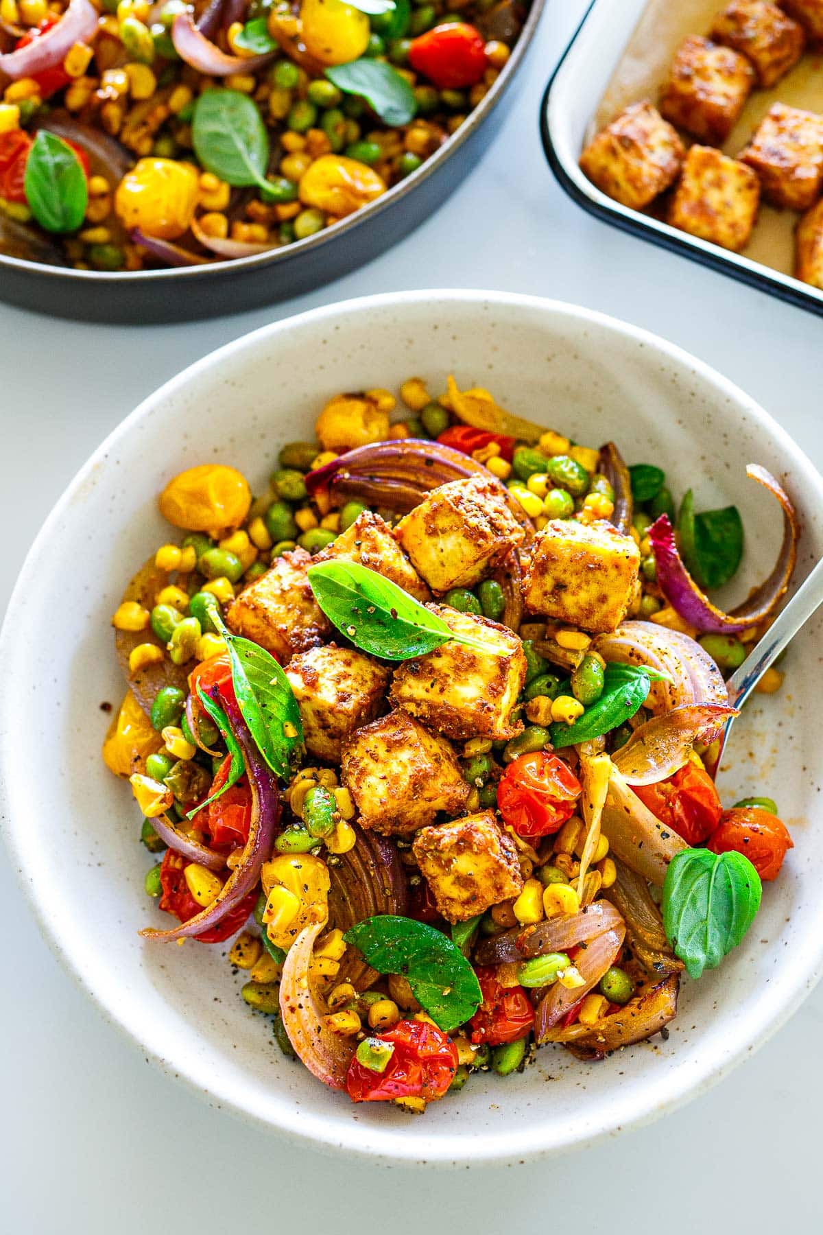 sheet pan succotash topped with crispy tofu in a white bowl. 