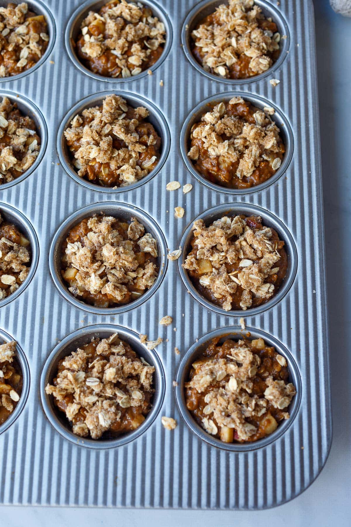 apple oat muffin batter poured into muffin tin. 