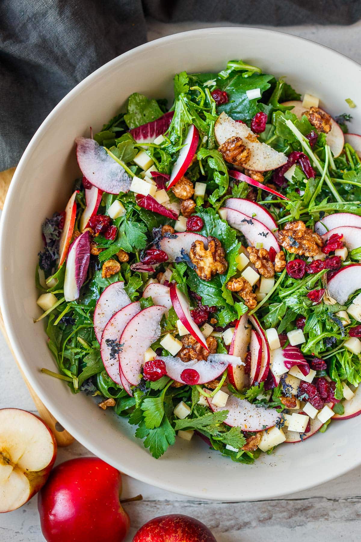 apple salad with walnuts and white cheddar in a white bowl.