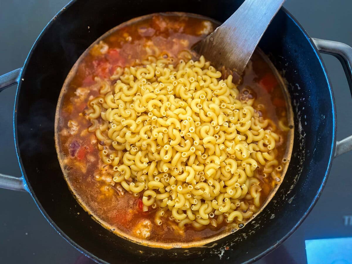 dried macaroni noodles added to large pot with broth.