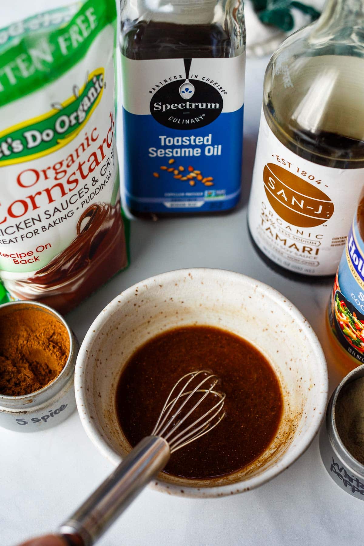 small bowl with stir fry sauce and whisk surrounded by ingredients.